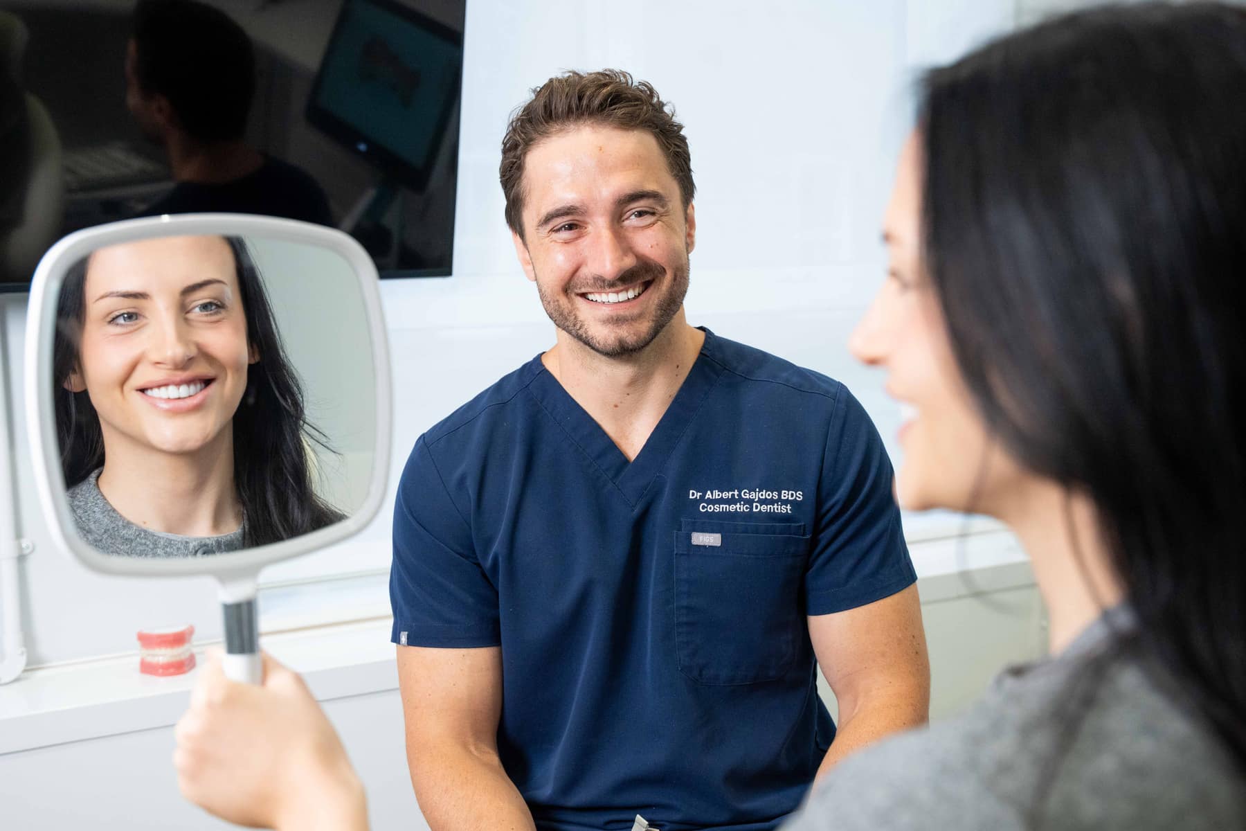 A patient reviewing her new smile in the mirror with cosmetic dentist Dr. Albert Gajdos at Smile Rooms Windsor